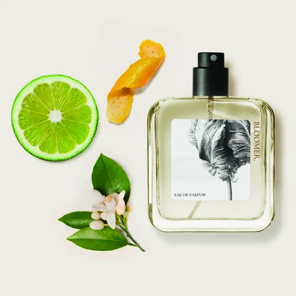 Perfume bottle with citrus slice, orange peel, and flowers by Reiko Lauper