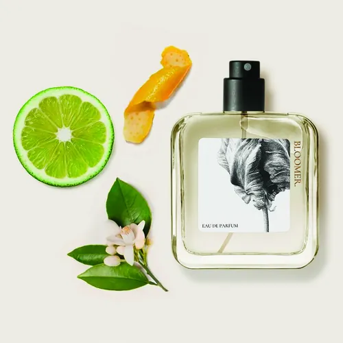 Perfume bottle with citrus slice, orange peel, and flowers by Reiko Lauper