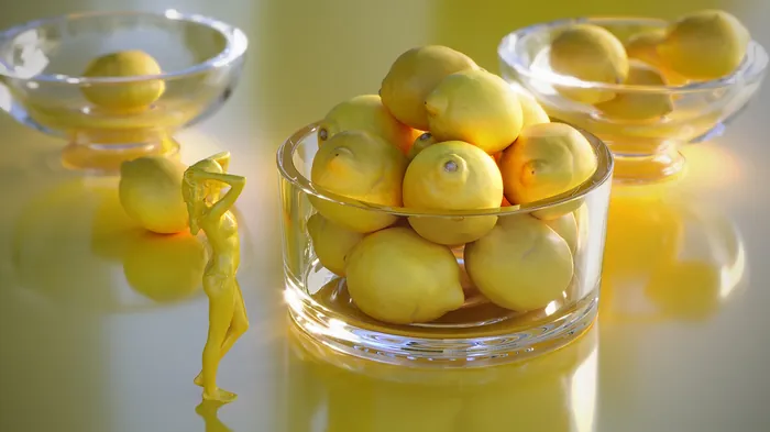 Glass bowls filled with lemons on a yellow reflective surface by RIVE GAUCHE
