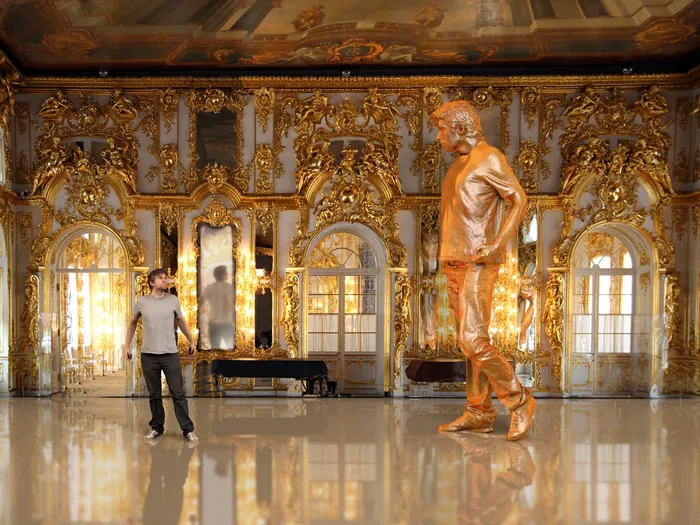 Man standing next to a golden statue in a gilded ornate room by RIVE GAUCHE