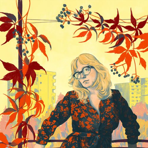 Woman in floral dress with glasses among red autumn leaves on balcony