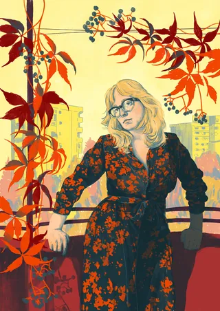 Woman in floral dress with glasses among red autumn leaves on balcony