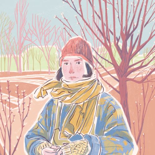Person wearing winter coat, scarf, and gloves standing outside near leafless trees.