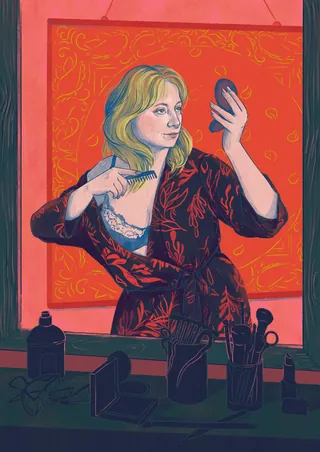 Woman combing her hair while looking in a handheld mirror