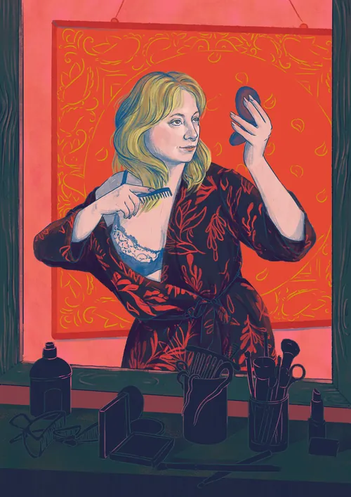 Woman combing her hair while looking in a handheld mirror