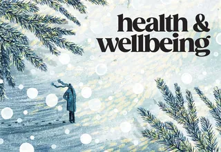 Woman standing under snow-covered evergreen branches by Rosanna Tasker