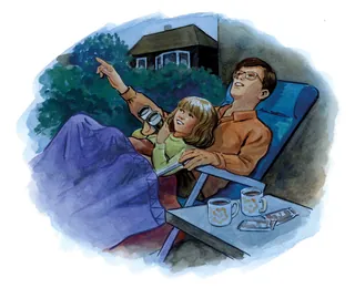 Father and daughter lying outside pointing at stars with mugs nearby