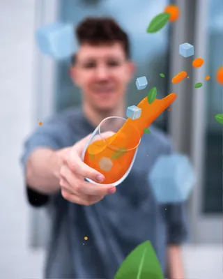 Glass of orange juice with falling ice cubes and leaves by Samy Löwe