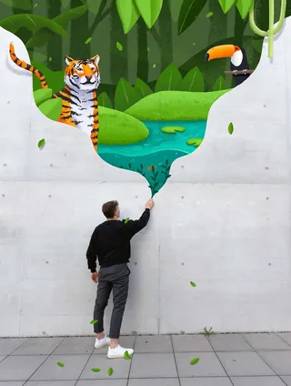 Man painting tiger and toucan jungle scene on wall by Samy Löwe