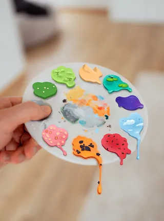 Paint palette with different colors and hand holding it