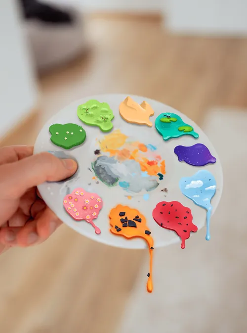 Paint palette with different colors and hand holding it
