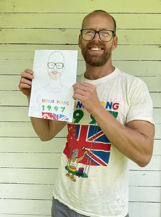 Man with glasses holding hand-drawn portrait of himself