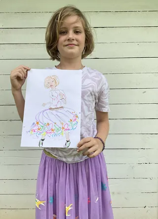 Young girl holding colorful drawing outdoors