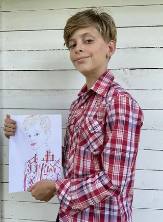 Tween boy in red plaid shirt holding self portrait drawing
