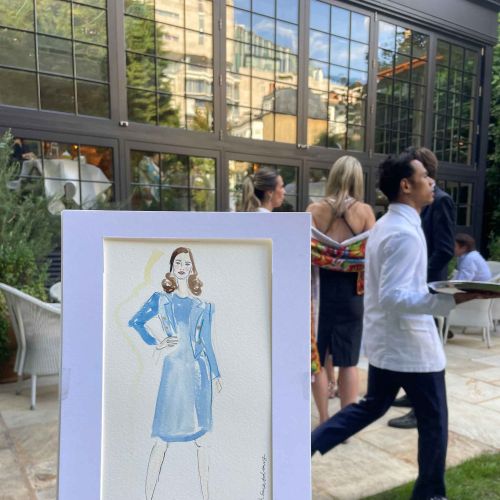 Live fashion illustration of woman in blue dress held outdoors