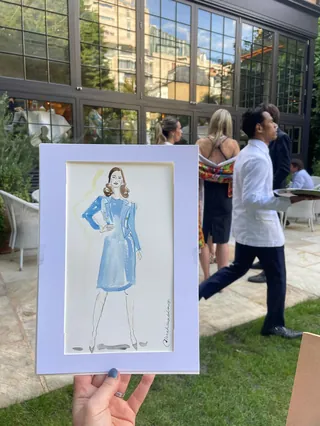 Live fashion illustration of woman in blue dress held outdoors