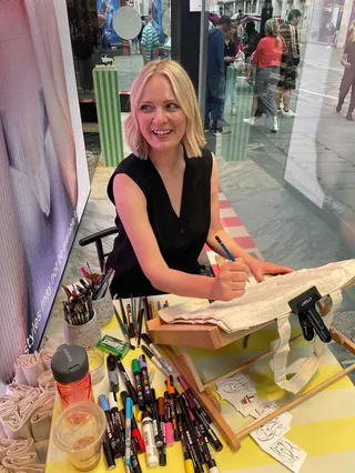 Artist painting live portrait on canvas tote bag at street store event