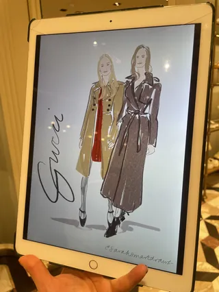Digital fashion illustration of two women in coats on iPad screen
