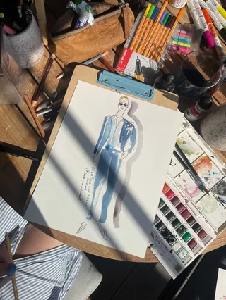 Live fashion illustration of a man in a blue suit with art supplies