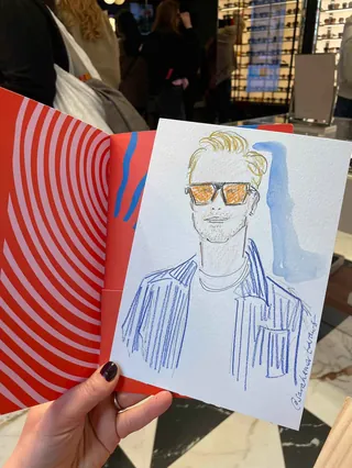 Hand holding illustrated portrait of man wearing sunglasses