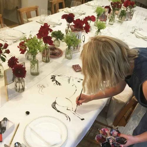 Artist painting live tablescape with floral decor at fashion event