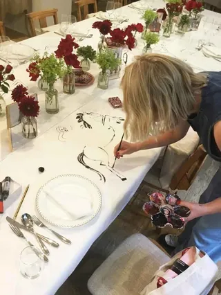 Artist painting live tablescape with floral decor at fashion event