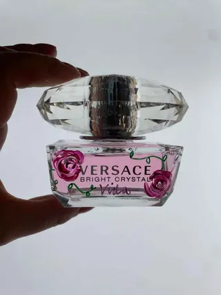 Hand holding a Versace Bright Crystal perfume bottle with floral design