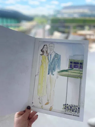 Hand holding watercolor painting of couple near Wimbledon tennis court