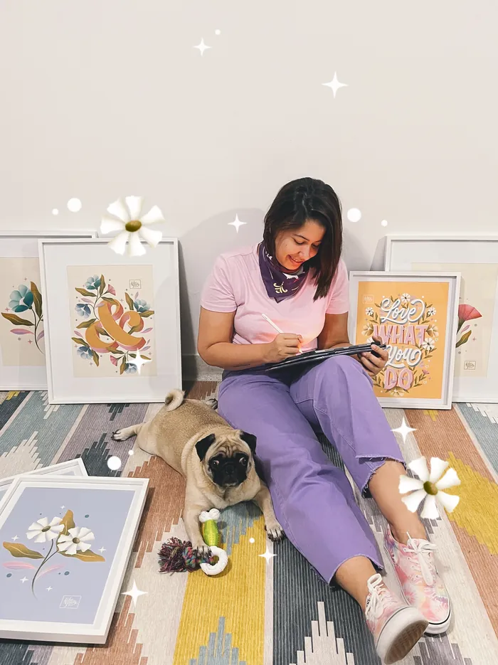 Woman sketching on floor with framed artwork and a dog nearby by Saskia Bueno
