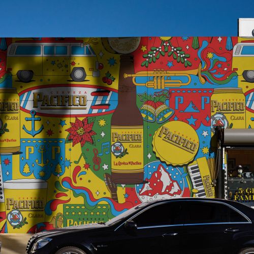 Colorful mural behind a black car, artwork by Season of Victory