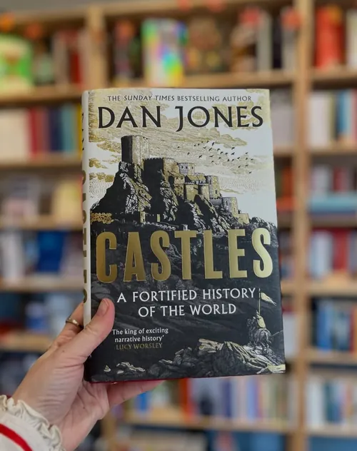 Studio Duco photograph of the Castles book cover held before a bookshelf