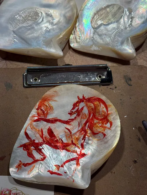 Hand-painted mother-of-pearl shells with red horse designs by Sunwoo Mansour