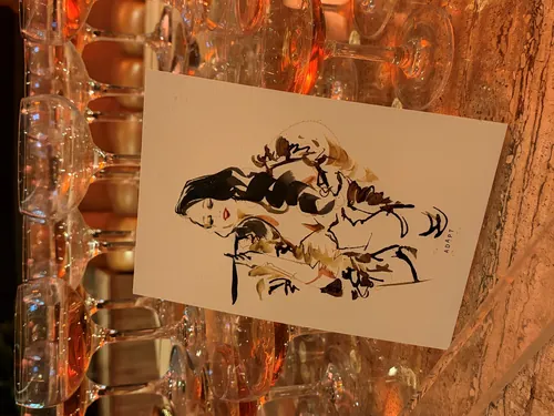 Live illustration card displayed among stacked champagne glasses by Sunwoo Mansour