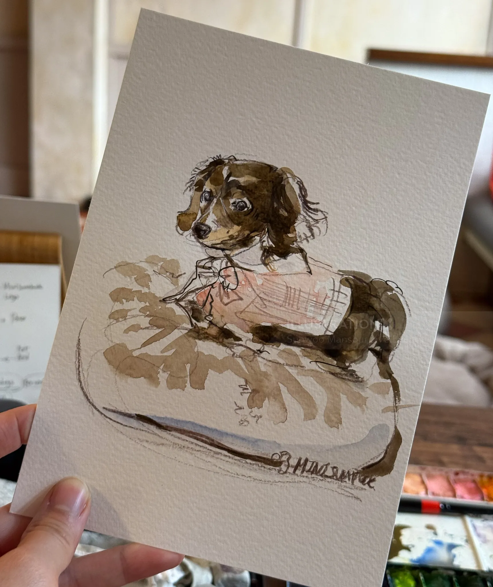 Watercolor painting of a small dog lying on a cushion by Sunwoo Mansour