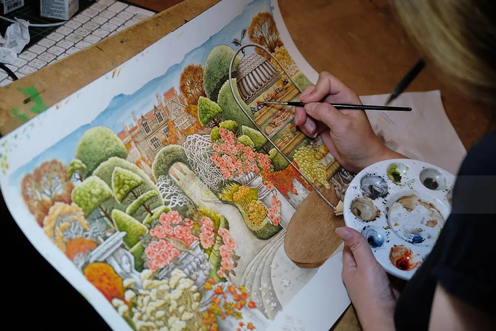 Person painting a colorful garden illustration with paintbrush and palette