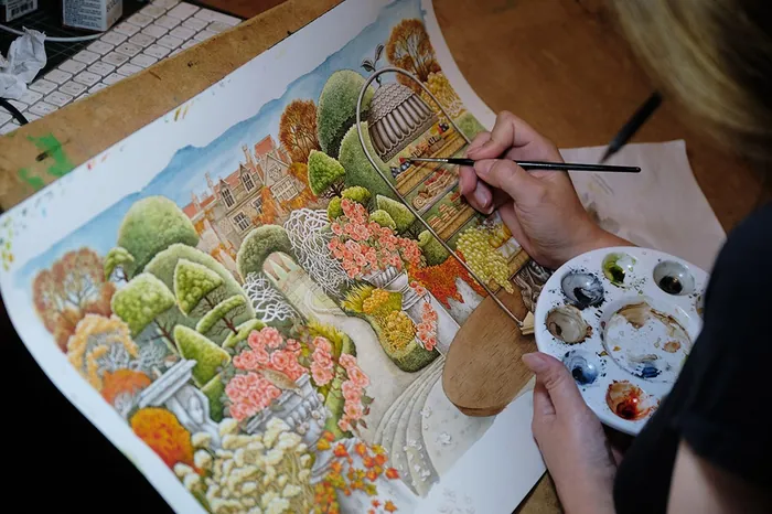 Person painting a colorful garden illustration with paintbrush and palette