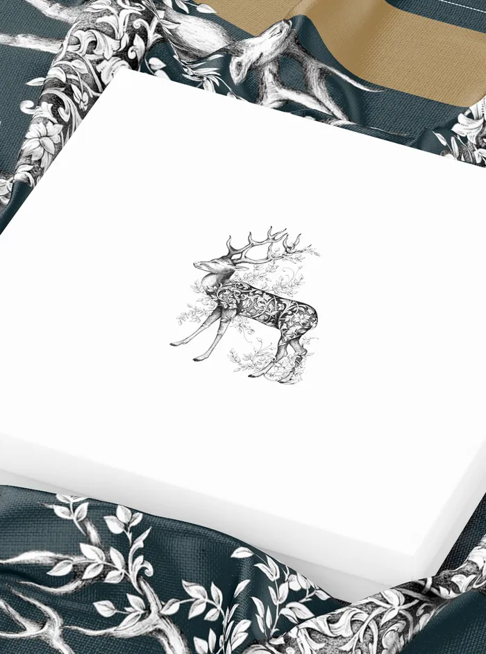 White packaging box with intricate reindeer design on fabric background