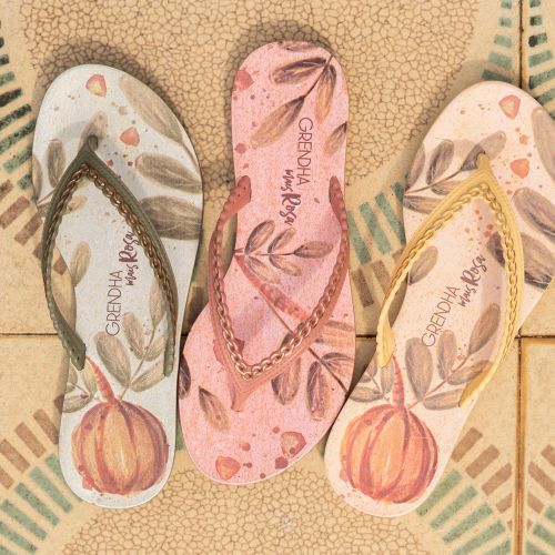 Three flip flops with printed designs on patterned tiled floor by Tai
