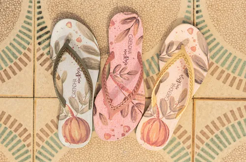 Three flip flops with printed designs on patterned tiled floor by Tai
