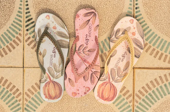 Three flip flops with printed designs on patterned tiled floor by Tai