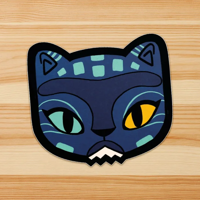 Stylized cat face with one green and one yellow eye on wooden surface