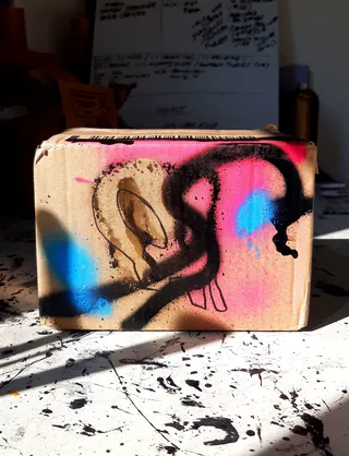 Cardboard box with colorful spray paint and skull drawing
