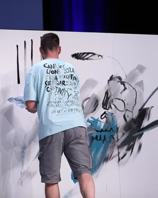 Artist painting a large abstract skull at Cannes Lions event