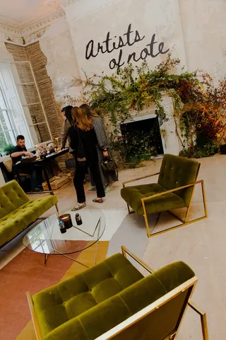 Artists chatting in a cozy studio with green chairs and plants
