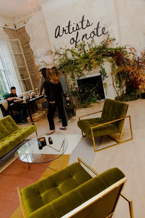 Artists chatting in a cozy studio with green chairs and plants