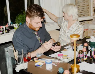 Man painting crafts while woman looks away at table with art supplies