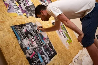 Man creating mixed media artwork on wooden wall