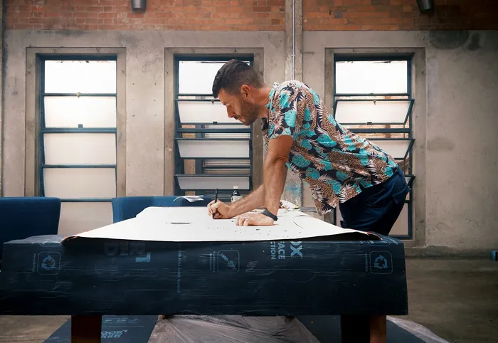 Man sketching on large paper in creative studio with brick walls