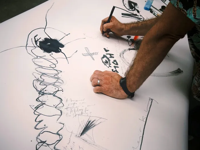 Person drawing abstract sketches and notes on large white paper