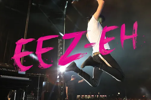 Musician jumping mid-air on stage with bright pink EEZ EH text
